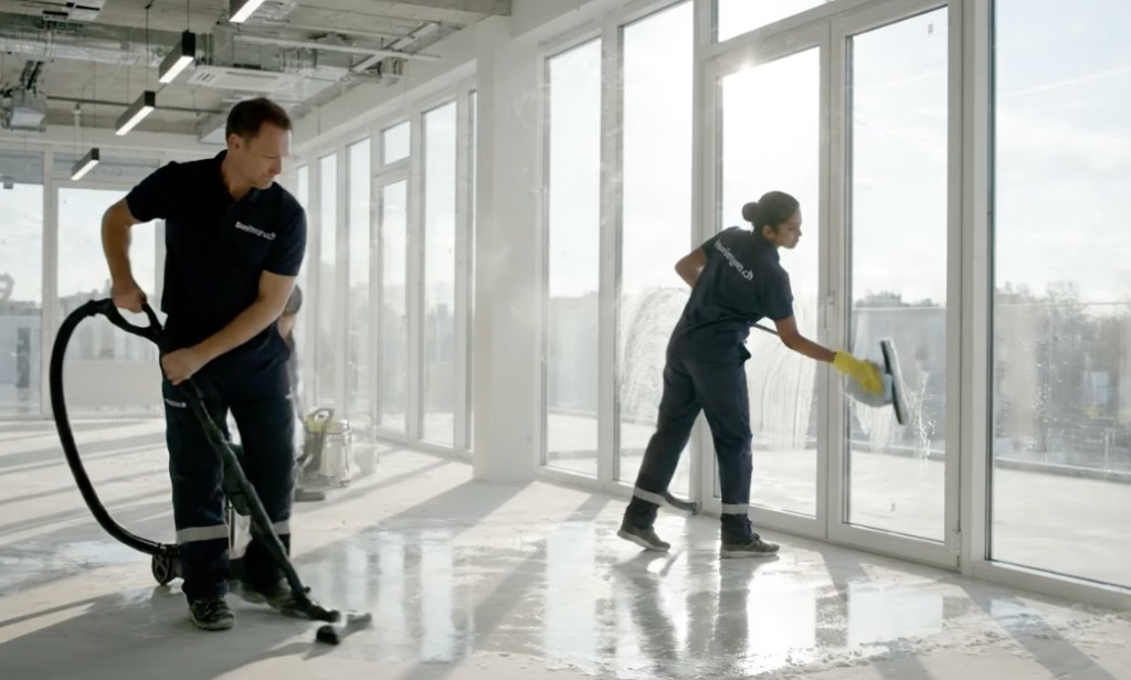 Zwei Baureiniger von baureiniger.ch bei Endreinigung: Nassboden und Glasfront in einem modernen Büro